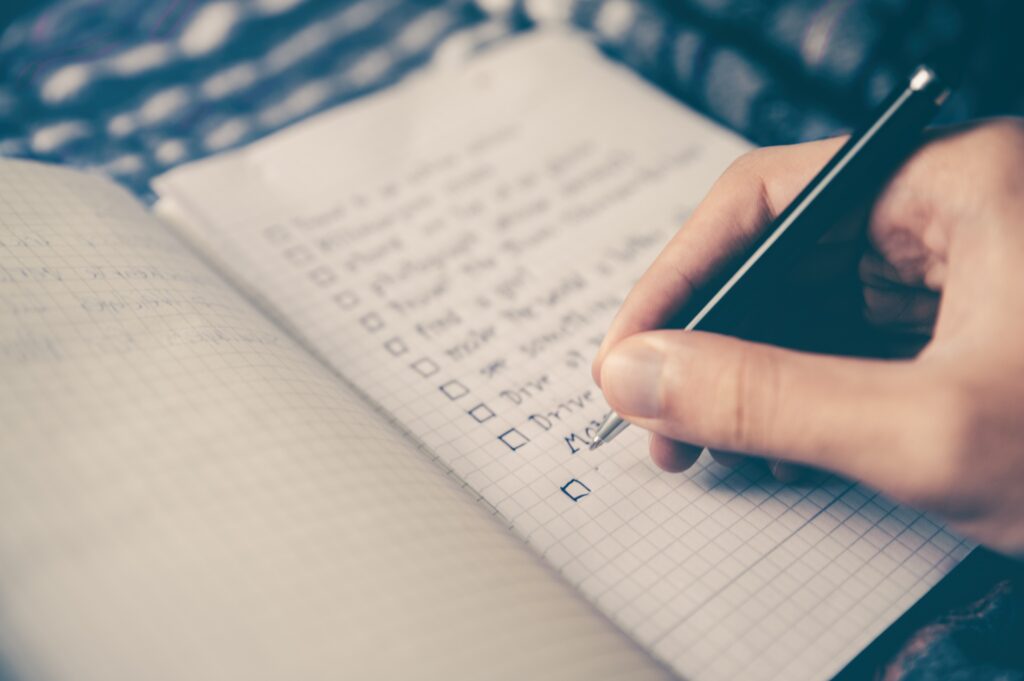 person writing a checklist in a notebook